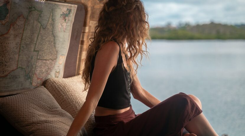 woman wearing black spaghetti strap top sitting viewing body of water