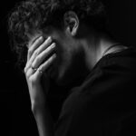 a black and white photo of a man covering his face