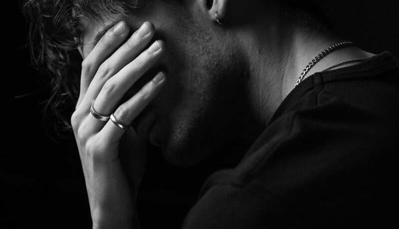 a black and white photo of a man covering his face