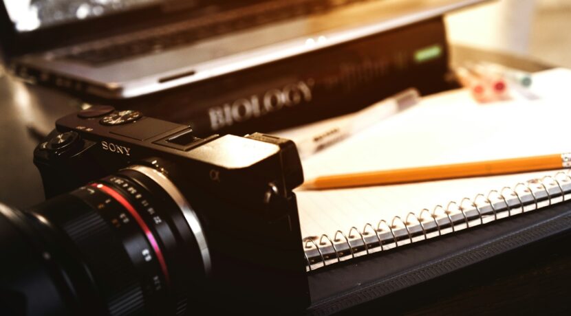 Sony compact camera near open spring notebook and pencil