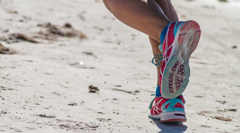 woman in white red and blue sneakers sitting on white sand during daytime