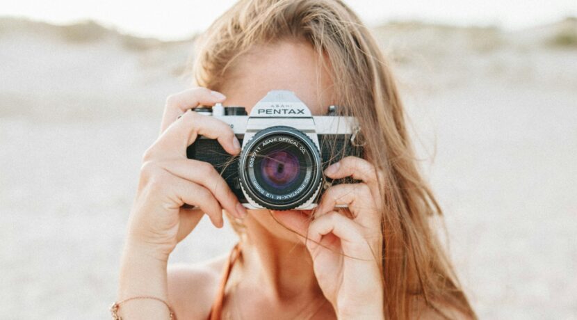 woman taking picture using silver Pentax camera