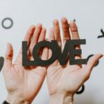 person holding love word cutout paper