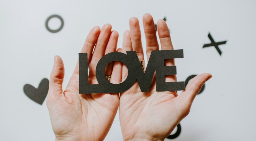 person holding love word cutout paper