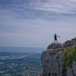 woman standing on cliff overlooking city during daytime