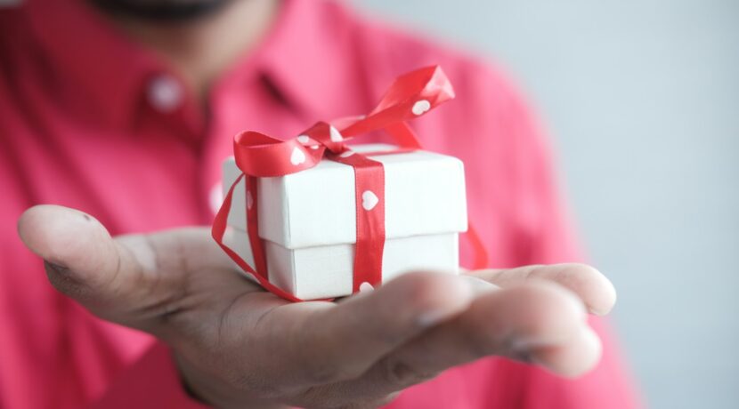 a man holding a white gift box with a red ribbon