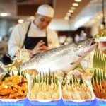 man in white apron holding fish