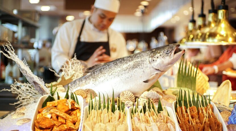man in white apron holding fish