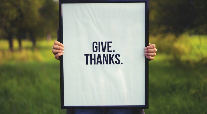 person holding rectangular black wooden photo frame with Give. Thanks. print