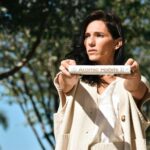 a woman holding up a tube with a label on it
