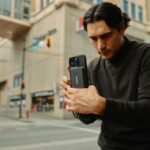 A man standing on the street looking at his cell phone