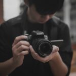 man in black shirt holding black nikon dslr camera
