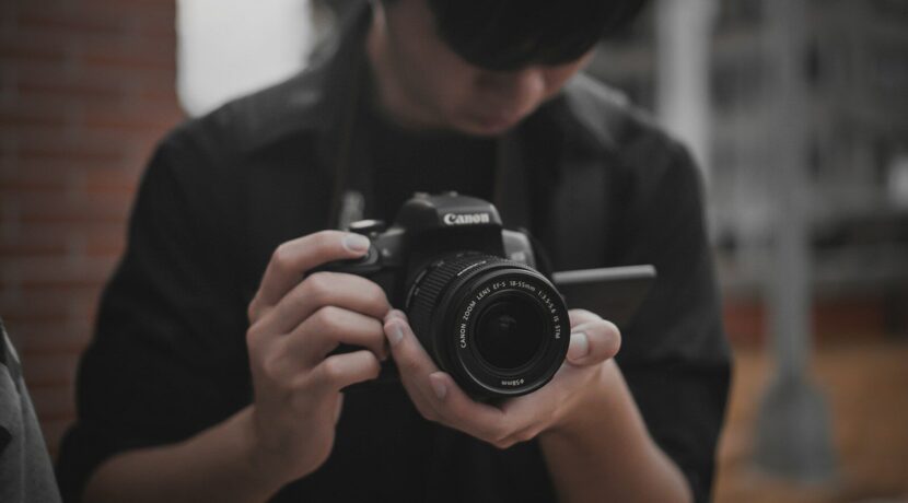 man in black shirt holding black nikon dslr camera