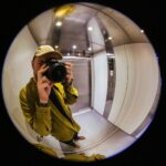 Man in yellow jacket takes selfie in elevator