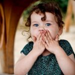 toddler holding her lips